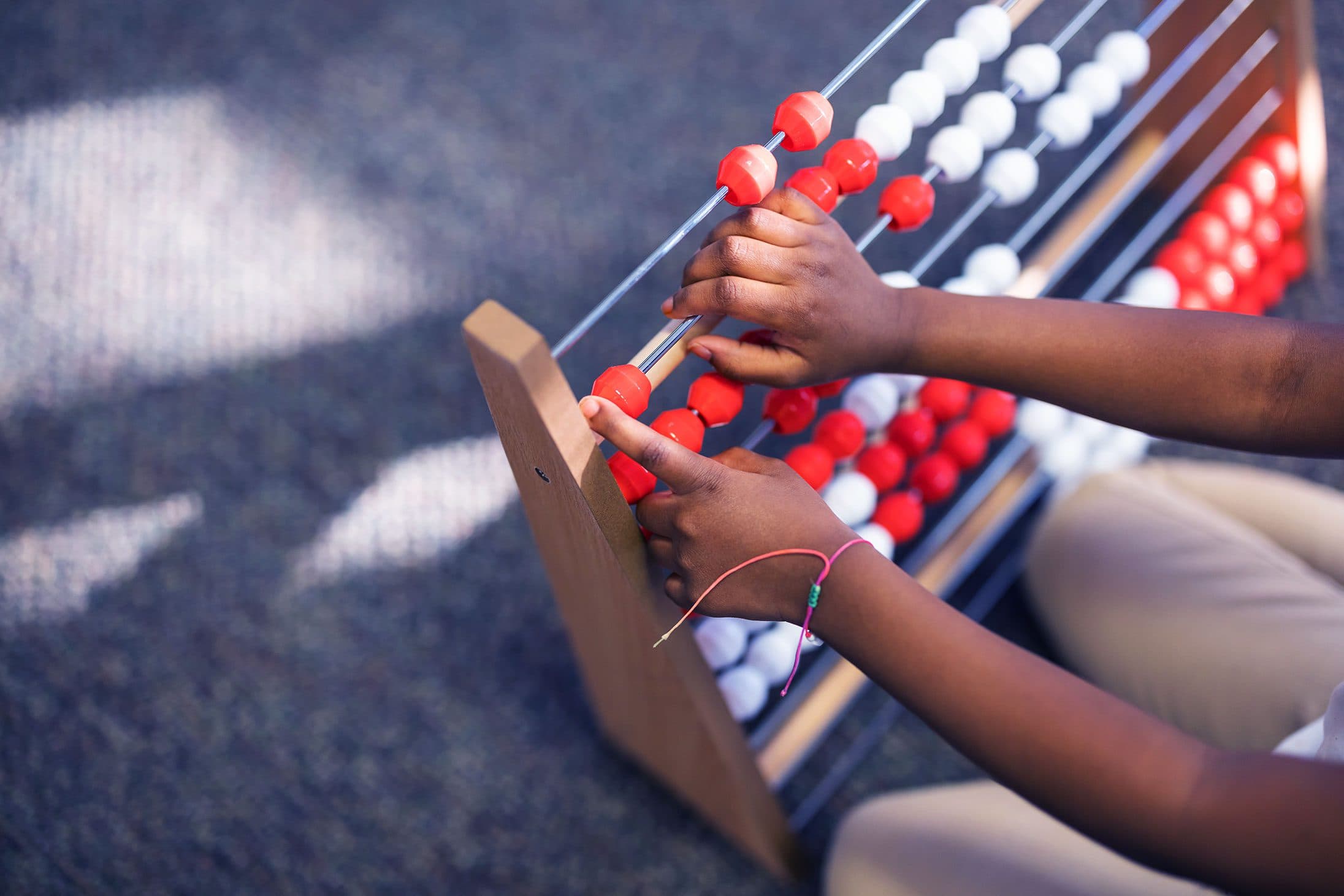 Student's hands moving beads on an abacus.