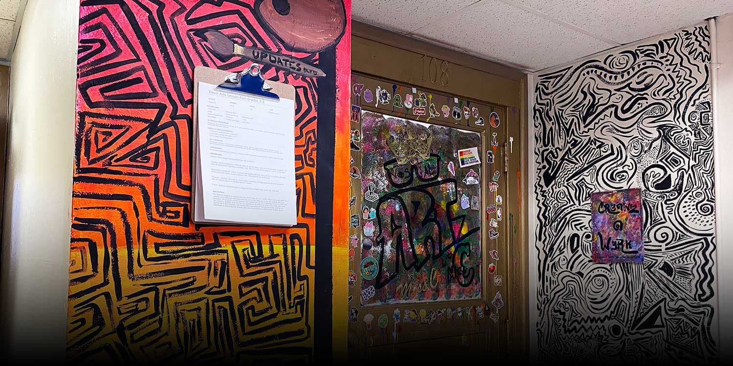 School hallway with painted abstract murals around an art-covered classroom door.