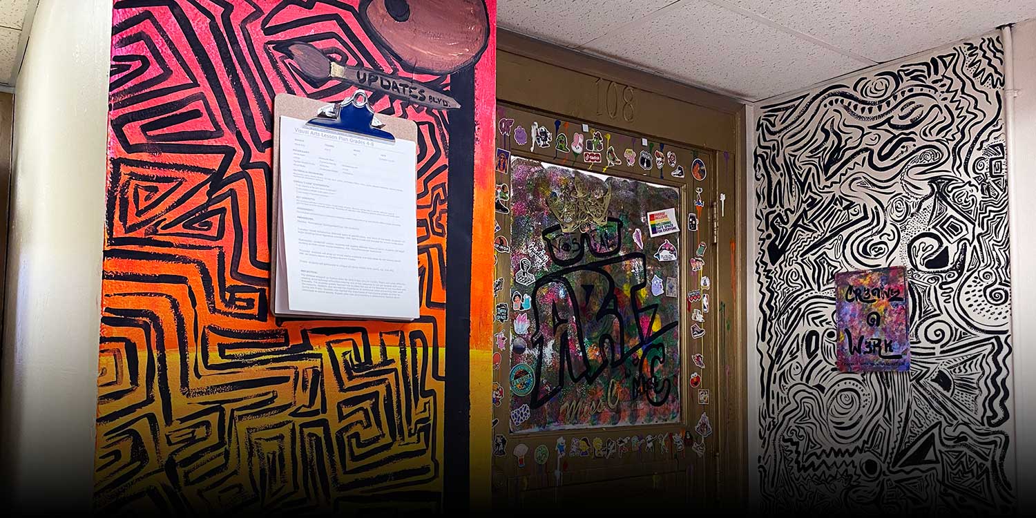 School hallway with painted abstract murals around an art-covered classroom door.