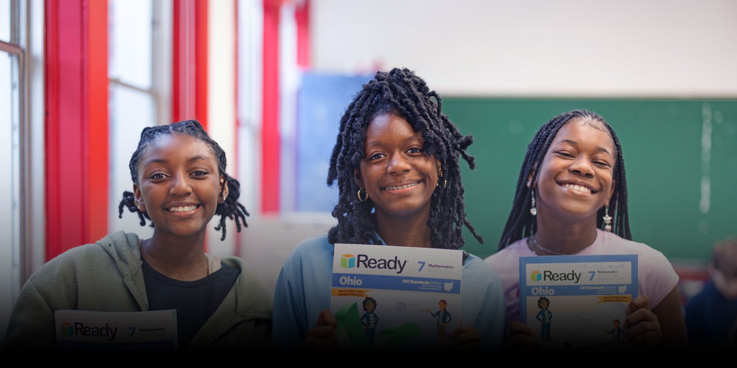 Three smiling students holding Ohio mathematics textbooks in a classroom.